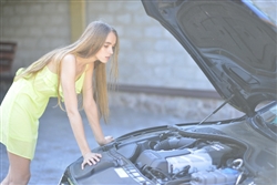 車が故障してエンジンルームを眺める女性